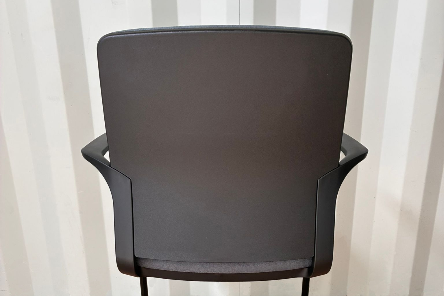 MAT - Cantilever Conference Chair 4 MAT Conference Office Chair with a black cantilever frame and dark gray upholstered padding positioned beside a white office desk and filing cabinet in a modern workspace